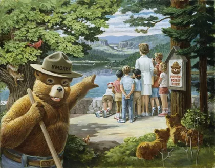 Pintura del oso Smokey sosteniendo una pala mientras señala a un grupo de visitantes que observan hacia el lago y el bosque por encima de un muro de piedra. Dos osos cachorros escondidos en el bosque observan a los visitantes.