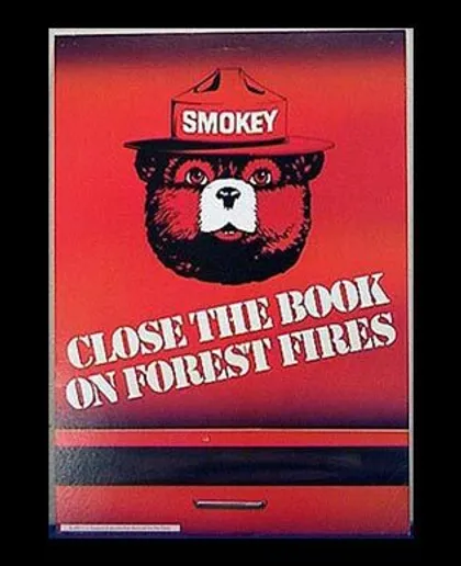 Un cartel con el oso Smokey en el centro que dice: "Cierra el libro sobre incendios forestales".