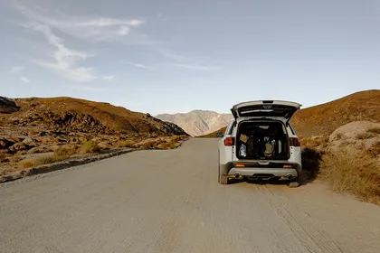 Carro con el maletero abierto aparcado en un camino de tierra