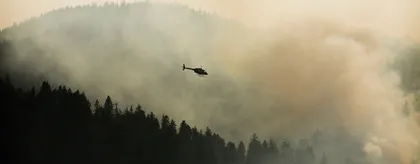 Helicóptero volando sobre un bosque en llamas
